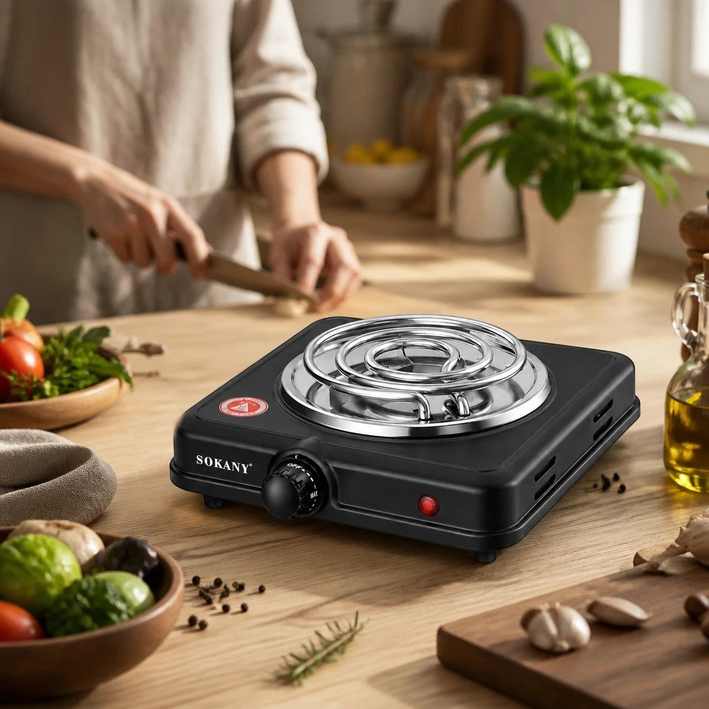 INOUTHOMECO SOKANY electric stove with a 1000W heating coil on a wooden kitchen counter while someone prepares food.